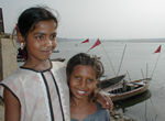 Two smiling kids and boats.  Of the three girls, only the girl in white goes to school.  She was very articulate and charming.  She sells tiny little votive candles made from a spot of wax and a wick on  a tiny dish about the size of a half dollar.  